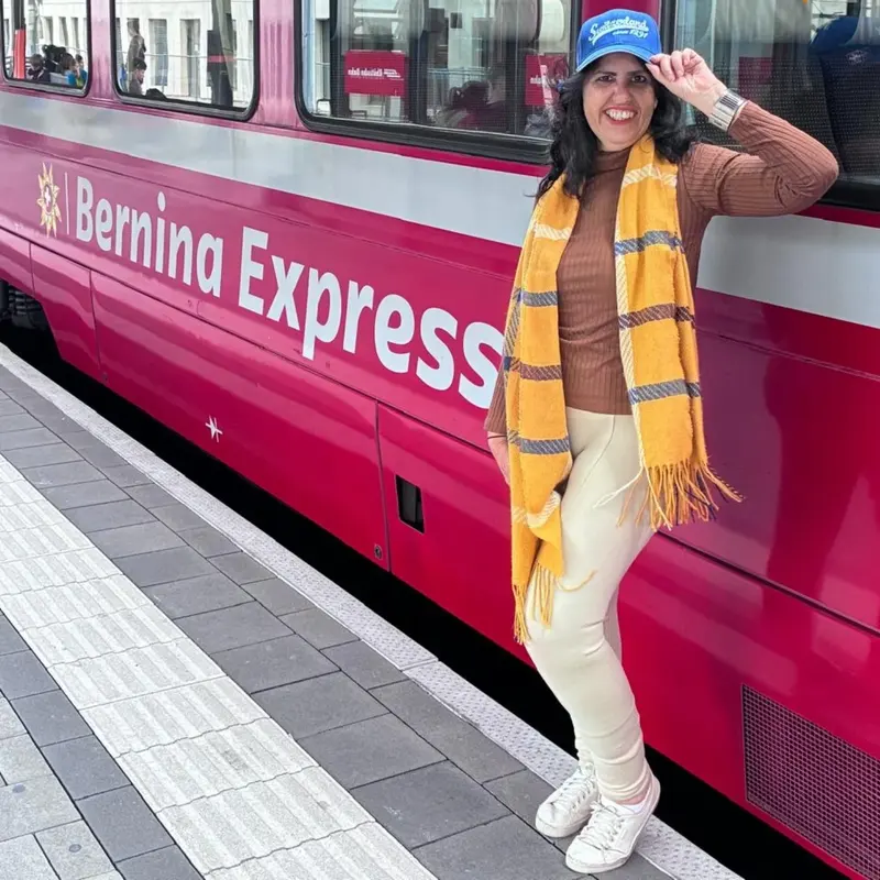 Lucyana ao lado do trem vermelho Bernina Express, na Suíça.