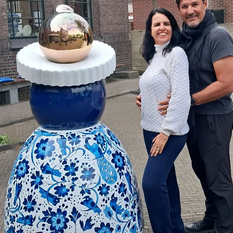 Casal ao lado de uma escultura de cerâmica azul e branca em Delft.