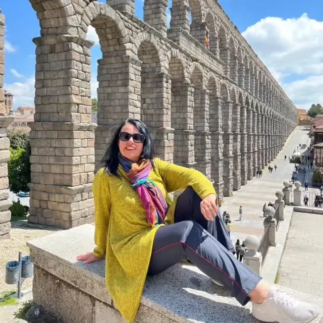 Viajante sentada diante dos arcos do aqueduto romano de Segóvia.