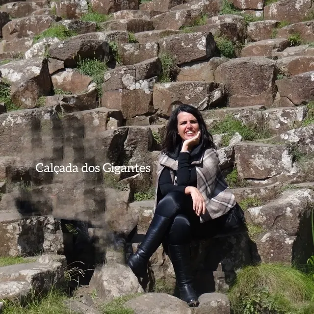 Viajante sentada sobre as colunas de basalto da Calçada dos Gigantes.