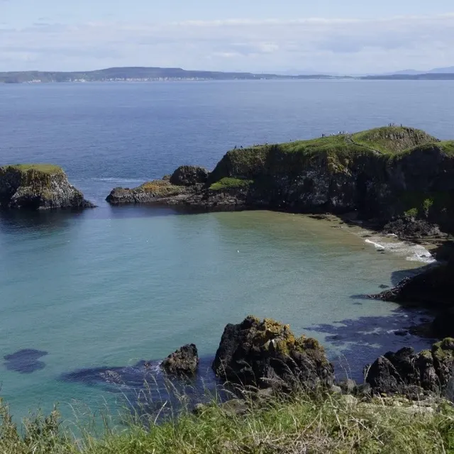 Costa recortada e mar azul perto da ponte Carrick-a-Rede, na Irlanda do Norte.