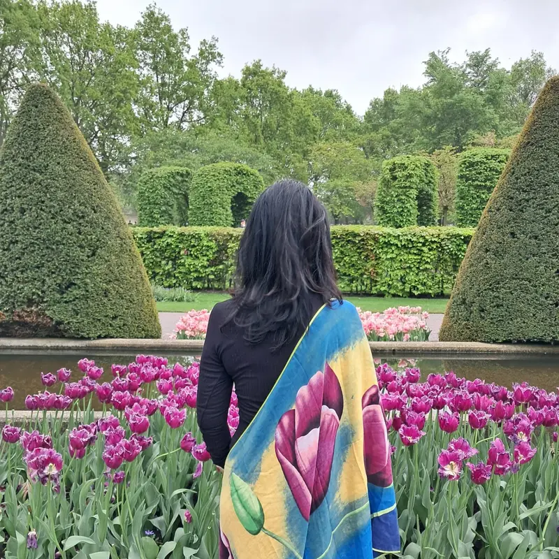 Lucyana de costas, com um lenço de tulipas, diante dos canteiros floridos do Keukenhof.