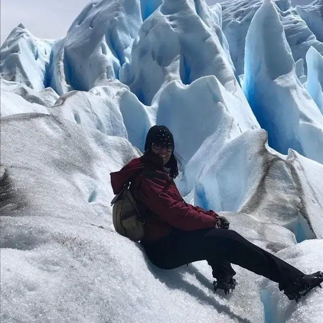 Viajante sentada sobre o gelo azulado do glaciar Perito Moreno.