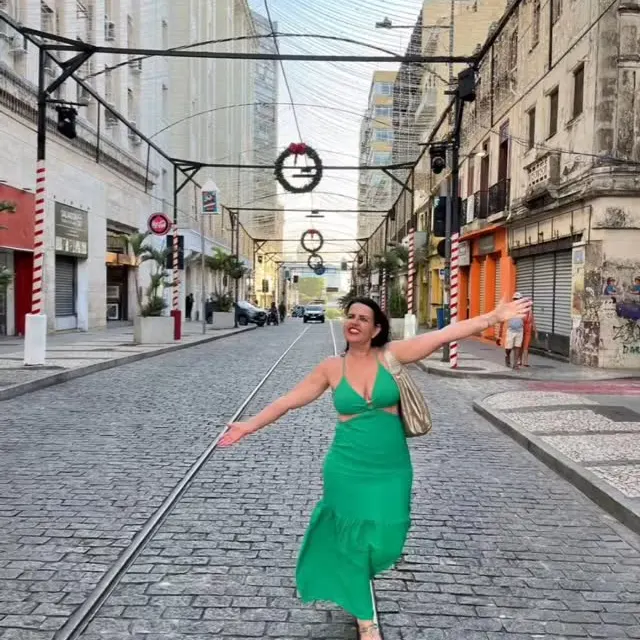 Viajante de vestido verde de braços abertos na Rua Chile, em Salvador.
